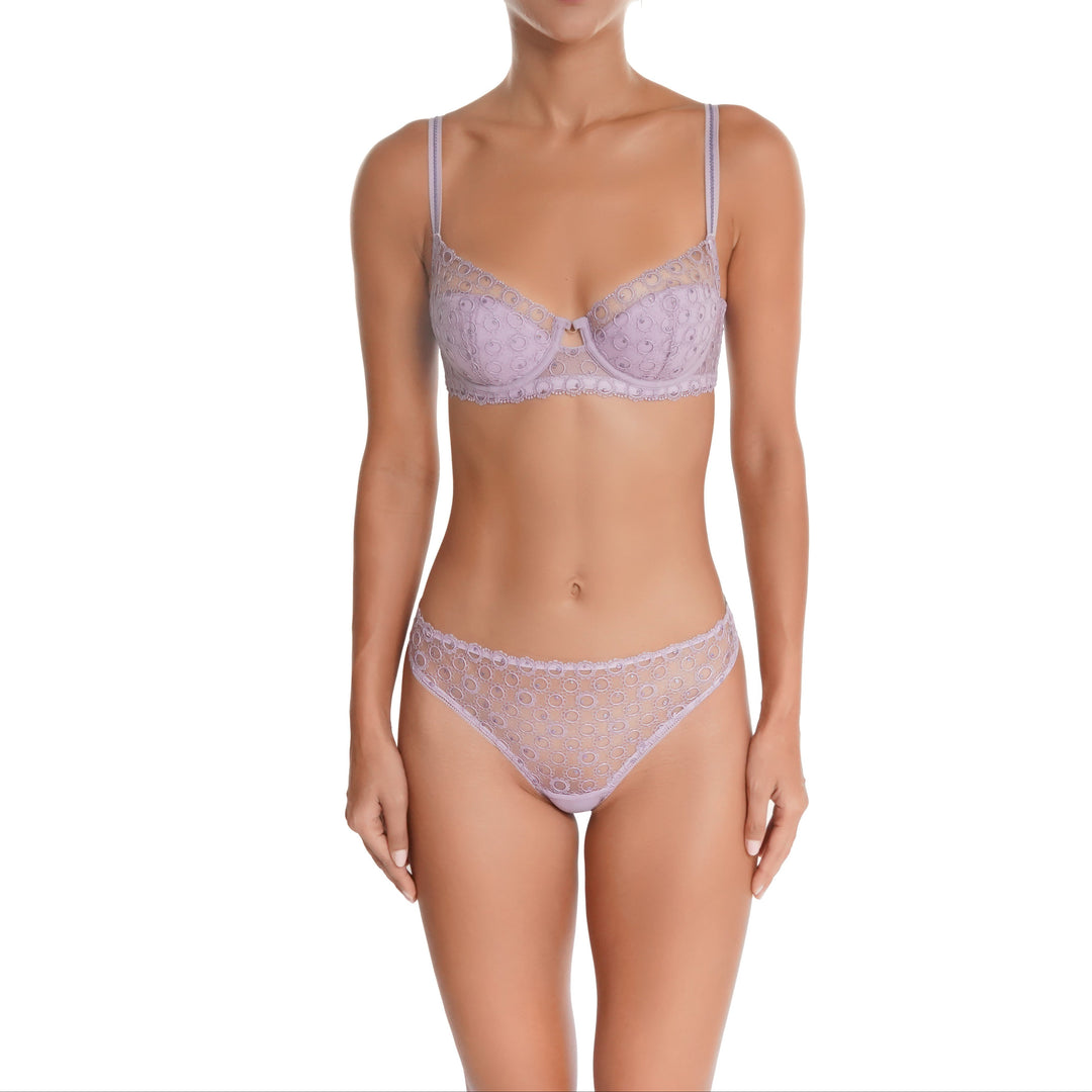 Woman wearing a lavender lace bra and panties set on a white background